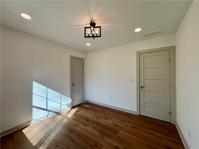 spare room with dark wood-type flooring, recessed lighting, baseboards, and visible vents