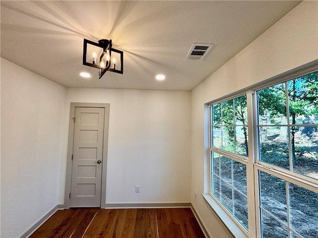 empty room with visible vents, baseboards, dark wood finished floors, recessed lighting, and an inviting chandelier