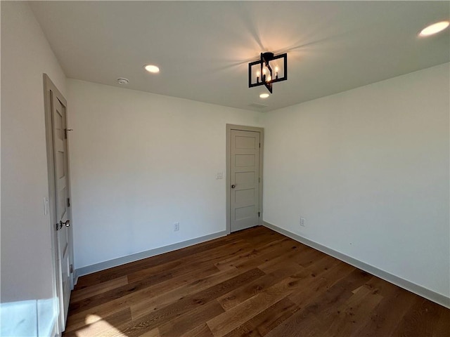 spare room with a notable chandelier, recessed lighting, wood finished floors, and baseboards