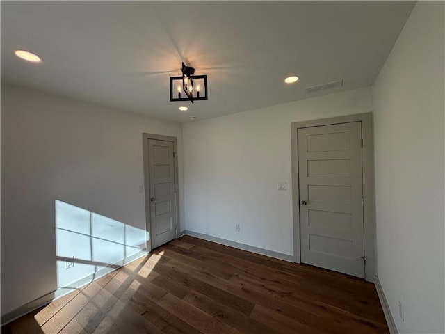 empty room featuring dark wood-type flooring, recessed lighting, visible vents, and baseboards