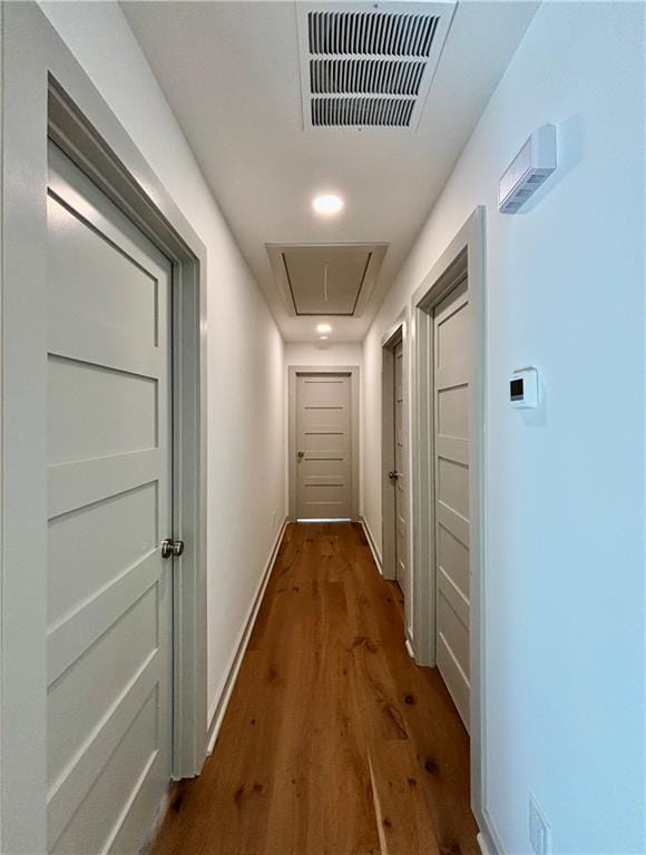 hall featuring visible vents, baseboards, attic access, and dark wood-style floors