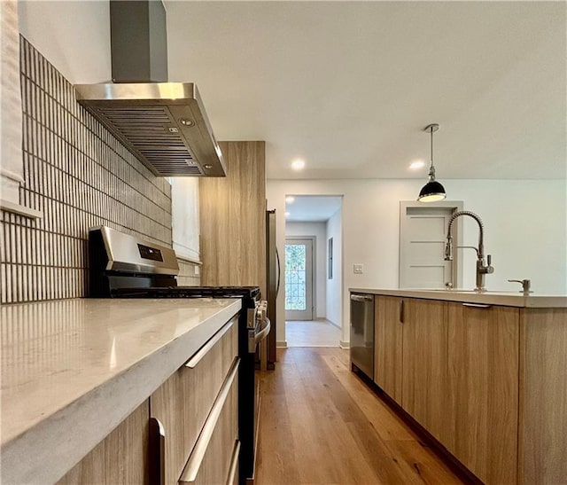 kitchen featuring modern cabinets, light wood-style flooring, appliances with stainless steel finishes, and exhaust hood