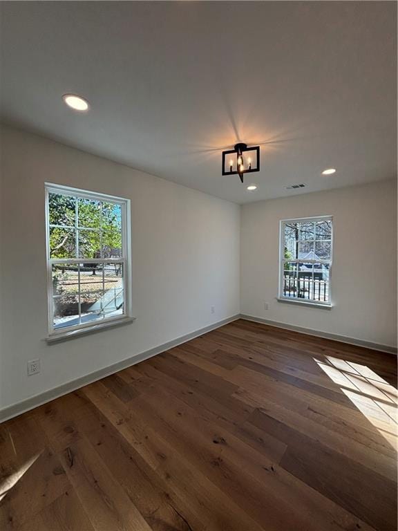 empty room with visible vents, recessed lighting, dark wood-type flooring, and baseboards