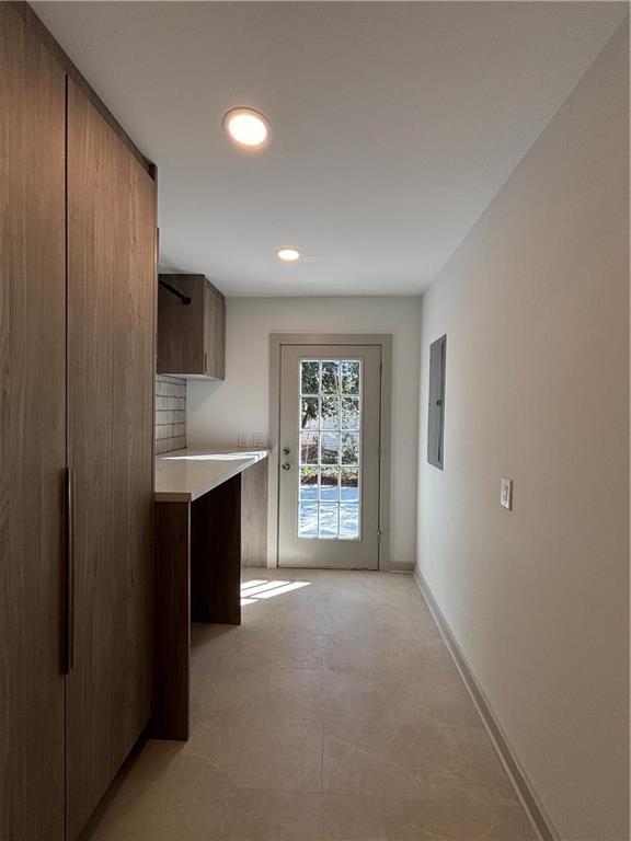 kitchen with baseboards, light countertops, electric panel, decorative backsplash, and recessed lighting