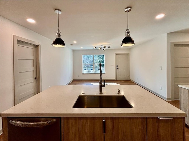 kitchen with a center island with sink, decorative light fixtures, open floor plan, and a sink