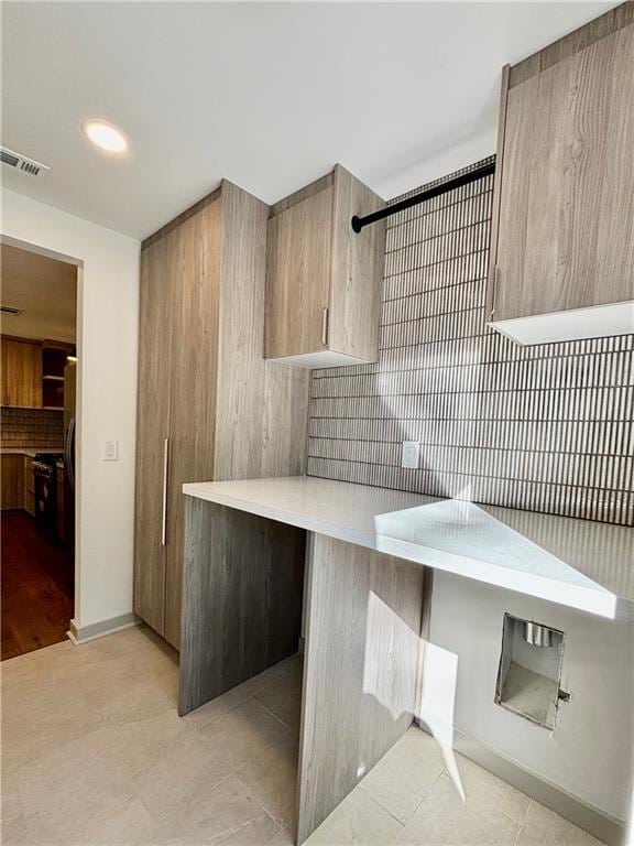 kitchen with visible vents, modern cabinets, backsplash, light countertops, and baseboards