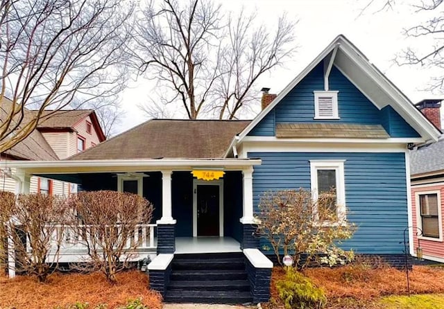 view of front facade with covered porch and a chimney