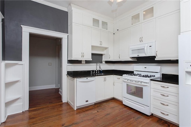 kitchen with white appliances, dark countertops, glass insert cabinets, and a sink