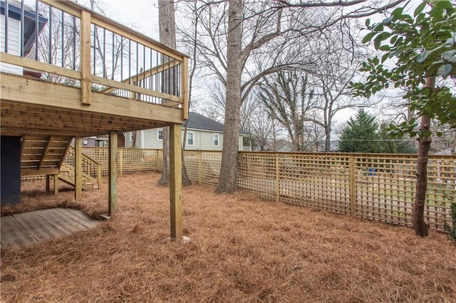 view of yard with a deck, a fenced backyard, and stairs