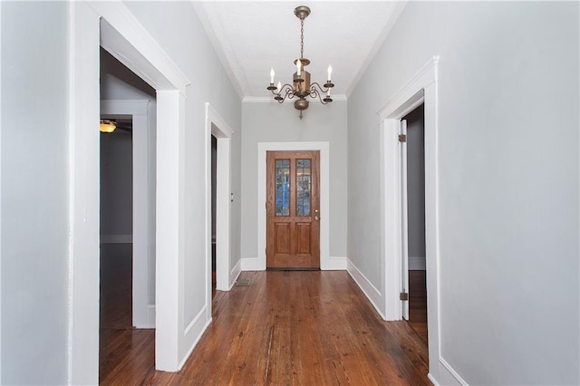 foyer entrance with crown molding, baseboards, wood-type flooring, and a chandelier