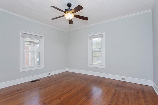 empty room featuring ceiling fan, hardwood / wood-style floors, baseboards, visible vents, and ornamental molding