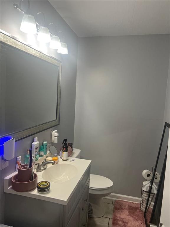 bathroom with toilet, tile patterned floors, baseboards, and vanity