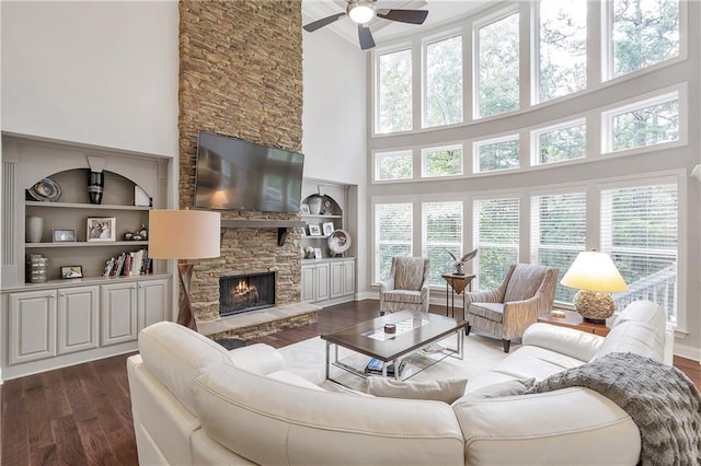 1546 Heritage Pass, Milton, GA 30004 - living area featuring dark wood-type flooring, a towering ceiling, a ceiling fan, a fireplace, and built in shelves
