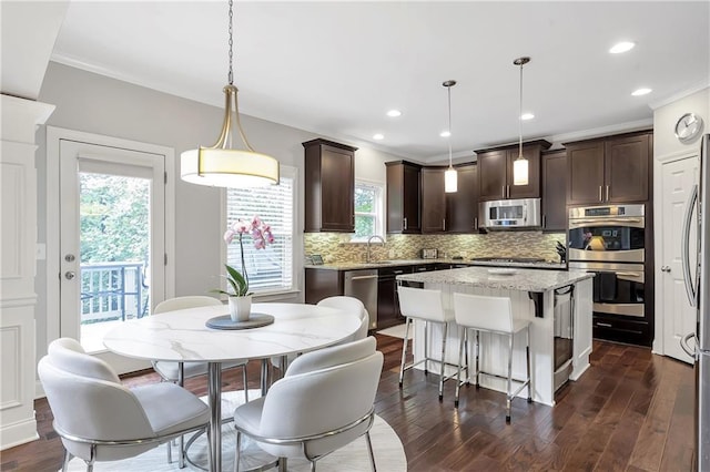 1546 Heritage Pass, Milton, GA 30004 - kitchen featuring appliances with stainless steel finishes, dark brown cabinets, backsplash, ornamental molding, and dark wood-style flooring