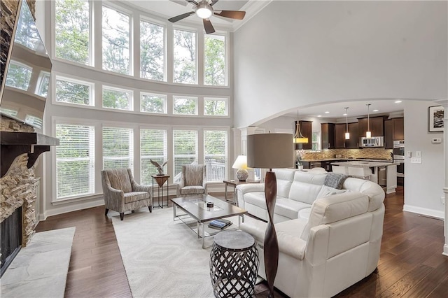 1546 Heritage Pass, Milton, GA 30004 - living room with a towering ceiling, a ceiling fan, plenty of natural light, a stone fireplace, and dark wood finished floors