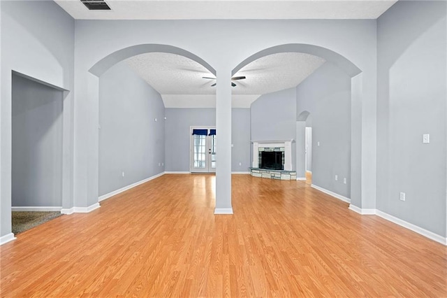 unfurnished living room featuring a textured ceiling, a stone fireplace, visible vents, baseboards, and light wood-type flooring