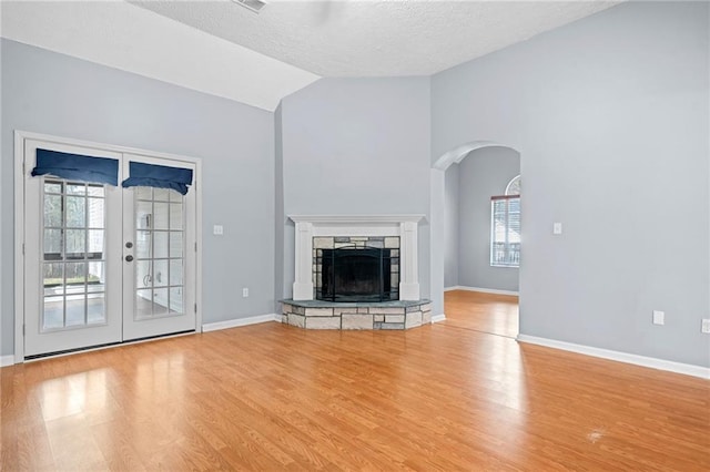 unfurnished living room featuring lofted ceiling, a fireplace, baseboards, and wood finished floors