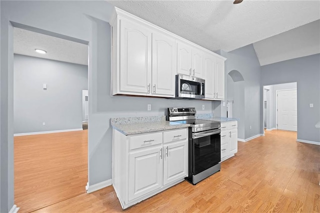 kitchen with light wood-type flooring, white cabinetry, stainless steel appliances, and arched walkways