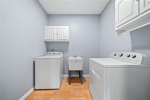 laundry area featuring light wood-style floors, cabinet space, washer and clothes dryer, and baseboards