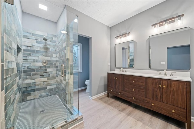 full bathroom with double vanity, wood finished floors, a stall shower, and a sink