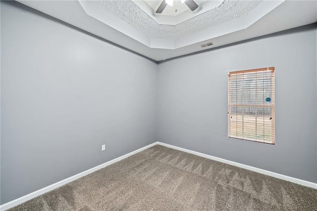 unfurnished room with carpet floors, a raised ceiling, and baseboards