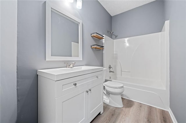 full bathroom featuring toilet, wood finished floors, tub / shower combination, a textured ceiling, and vanity