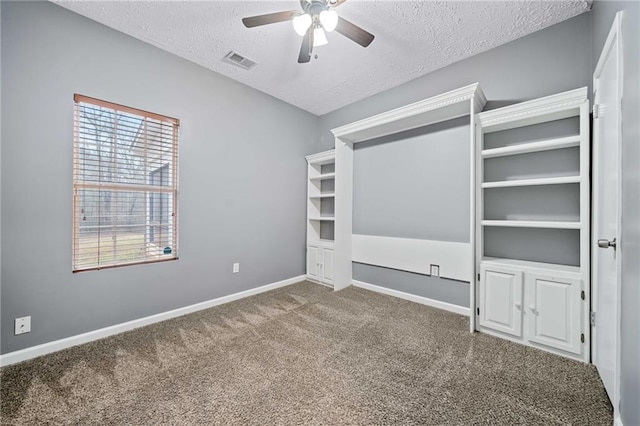 unfurnished bedroom with a textured ceiling, carpet flooring, a ceiling fan, visible vents, and baseboards