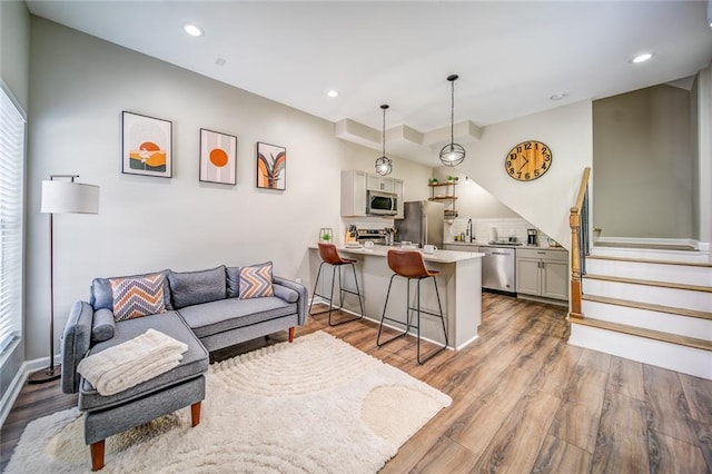 living area with recessed lighting, stairway, baseboards, and wood finished floors