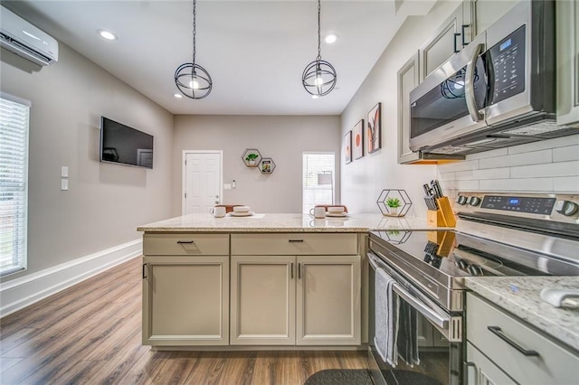 kitchen with dark wood finished floors, a wall unit AC, a peninsula, stainless steel appliances, and backsplash