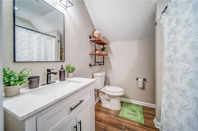 bathroom with lofted ceiling, toilet, wood finished floors, and vanity