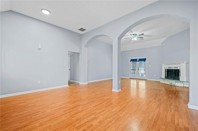 unfurnished living room with visible vents, baseboards, ceiling fan, a stone fireplace, and light wood-type flooring