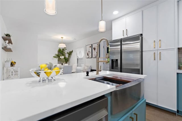 kitchen with stainless steel fridge with ice dispenser, white cabinets, light countertops, hanging light fixtures, and dark wood-type flooring