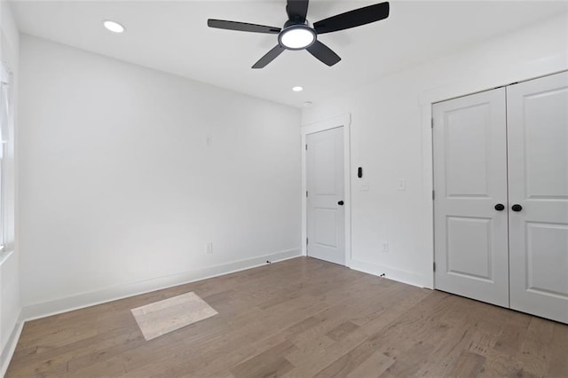 unfurnished bedroom featuring wood finished floors, baseboards, recessed lighting, a closet, and a ceiling fan