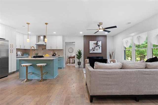 living room featuring recessed lighting, light wood-style floors, ceiling fan, and a fireplace