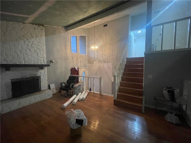 basement with hardwood / wood-style flooring, a stone fireplace, and an inviting chandelier