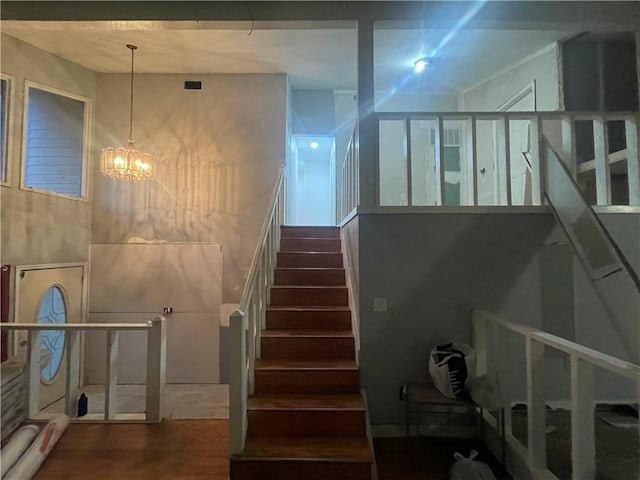 stairs with hardwood / wood-style floors and a notable chandelier