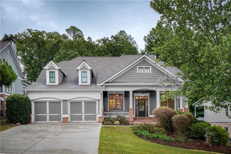 view of front of home featuring a front lawn, covered porch, and a garage