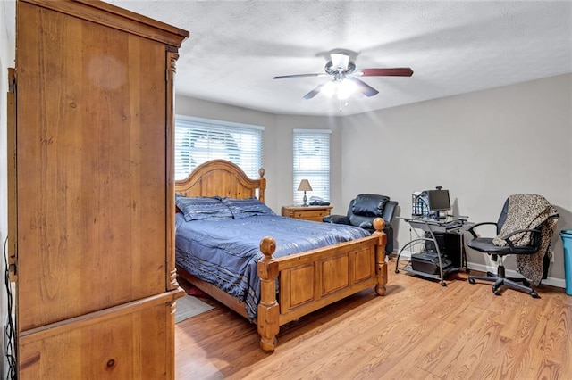 bedroom with ceiling fan, light hardwood / wood-style floors, and a textured ceiling