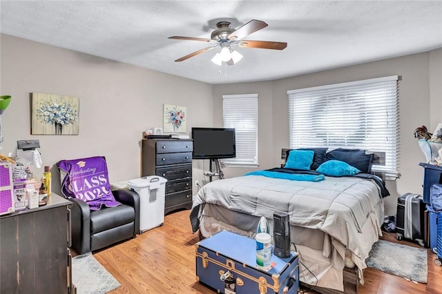 bedroom with ceiling fan, wood-type flooring, and a textured ceiling