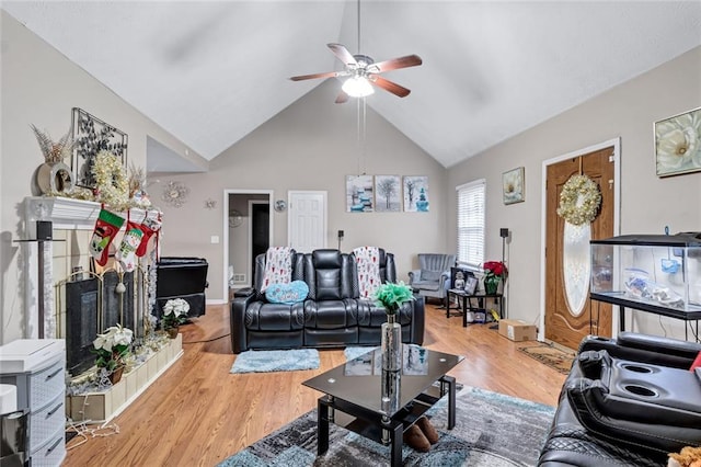 living room with a fireplace, ceiling fan, light hardwood / wood-style flooring, and high vaulted ceiling