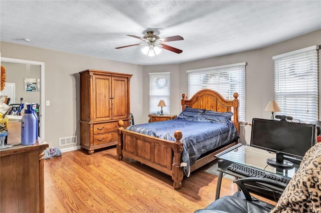 bedroom with ceiling fan, light hardwood / wood-style floors, and a textured ceiling