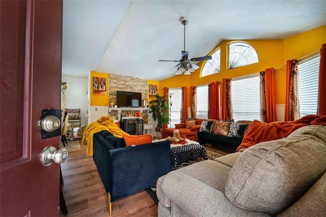 living area with a fireplace, wood finished floors, a healthy amount of sunlight, and vaulted ceiling