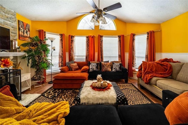 living area featuring lofted ceiling, a large fireplace, wood finished floors, and a textured ceiling