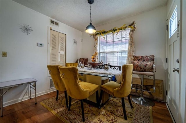 dining room featuring wood finished floors, visible vents, and a textured ceiling