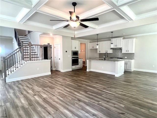 kitchen featuring ceiling fan, a center island with sink, white cabinets, oven, and stainless steel microwave