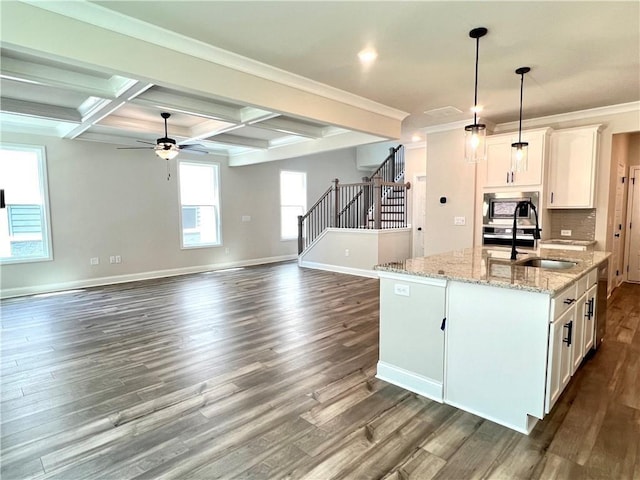 kitchen featuring coffered ceiling, a center island with sink, light stone countertops, beam ceiling, and white cabinetry