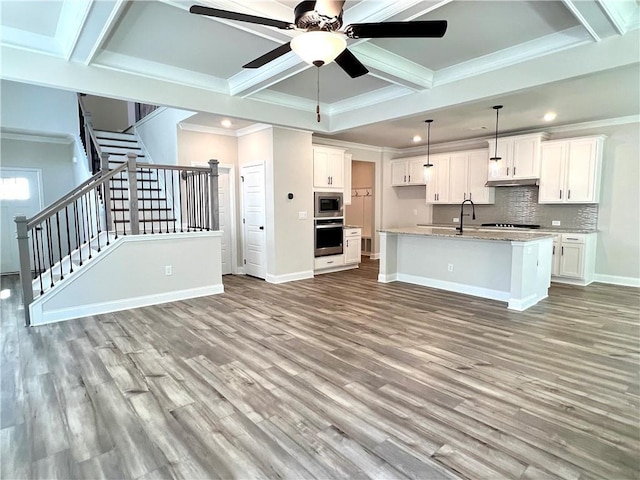 kitchen featuring ornamental molding, stainless steel appliances, a center island with sink, white cabinetry, and hanging light fixtures