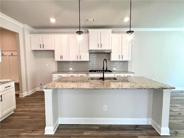 kitchen with white cabinets, a center island with sink, light stone countertops, and hanging light fixtures