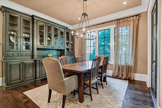 dining space featuring dark hardwood / wood-style flooring, an inviting chandelier, and crown molding