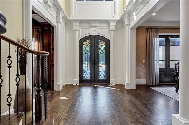 foyer entrance featuring dark hardwood / wood-style flooring, decorative columns, french doors, and crown molding